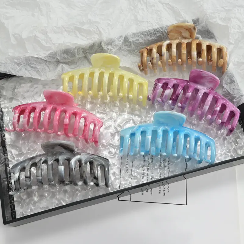 Six multi-color marble swirled large claw hair clips arranged inside gift packaging for thick hair updo styling