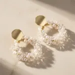 Gold round stud hoop earrings decorated with tiny pearl beads, elegant dainty jewelry for daily dating and wedding wear laid on soft beige background
