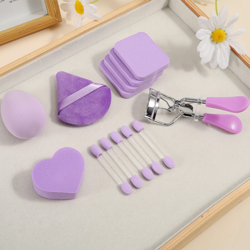 Purple full makeup tool set with beauty sponge, heart powder puffs, eyeshadow applicators and eyelash curler for daily makeup application