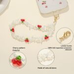 White natural stone beaded phone wrist strap decorated with red cherry ornaments and golden lobster clasp, used as an anti-lost decorative hand chain for mobile phones in daily use.